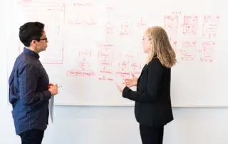 two people in front of a whiteboard demonstrating agile processes